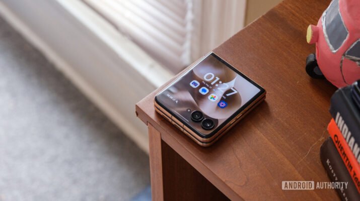 Visual elegan Motorola Razr Ultra 2025 dalam balutan warna Pantone Cabaret yang sedang dipajang dengan layar lipat 165Hz yang memukau di atas meja kayu minimalis.